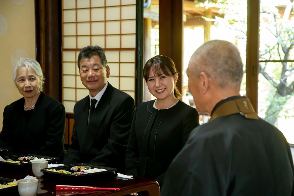 和室でお経を聞く喪服の人々