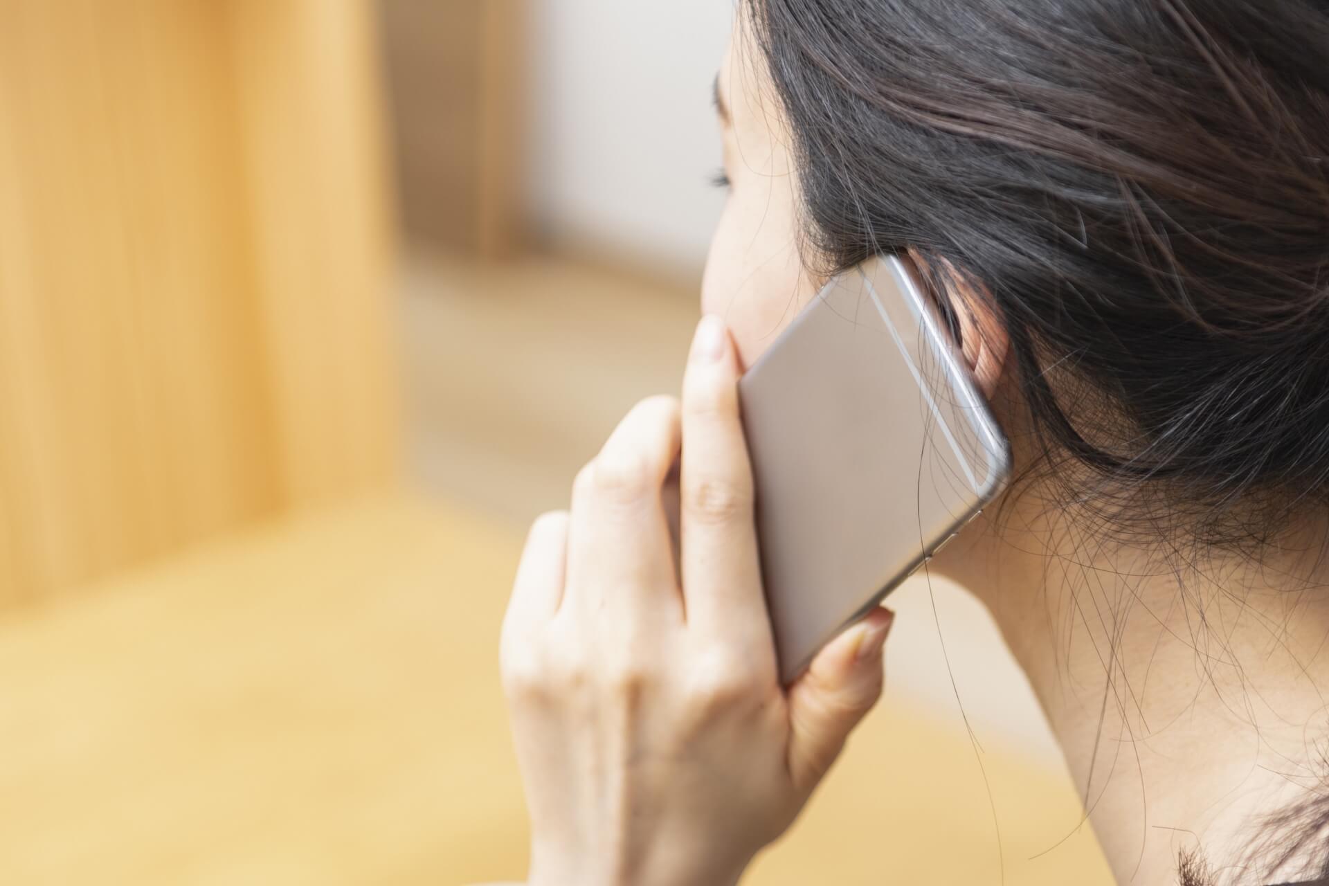 スマートフォンで通話する女性の後姿